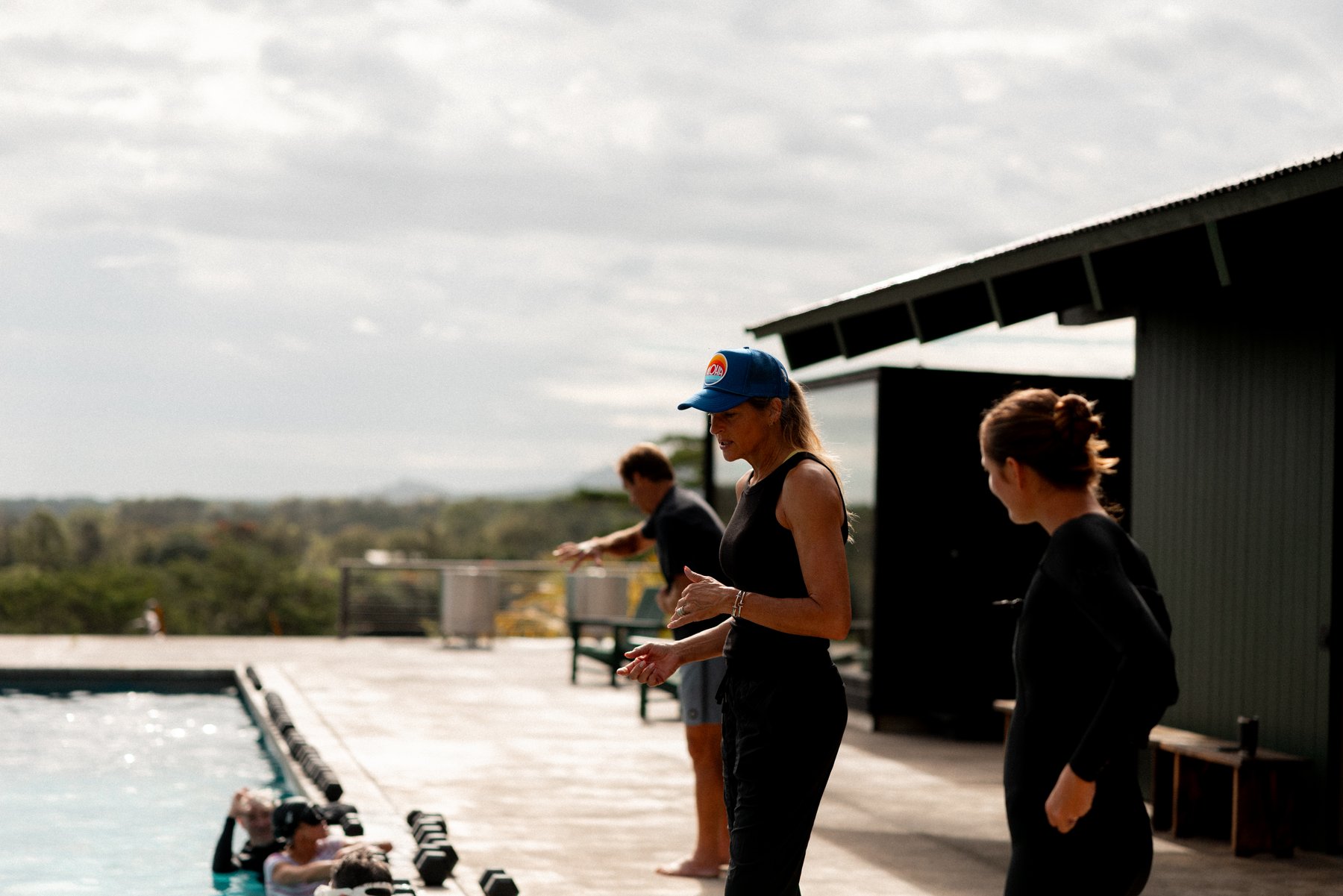 Gabby coaching at poolside while the group trains in the water