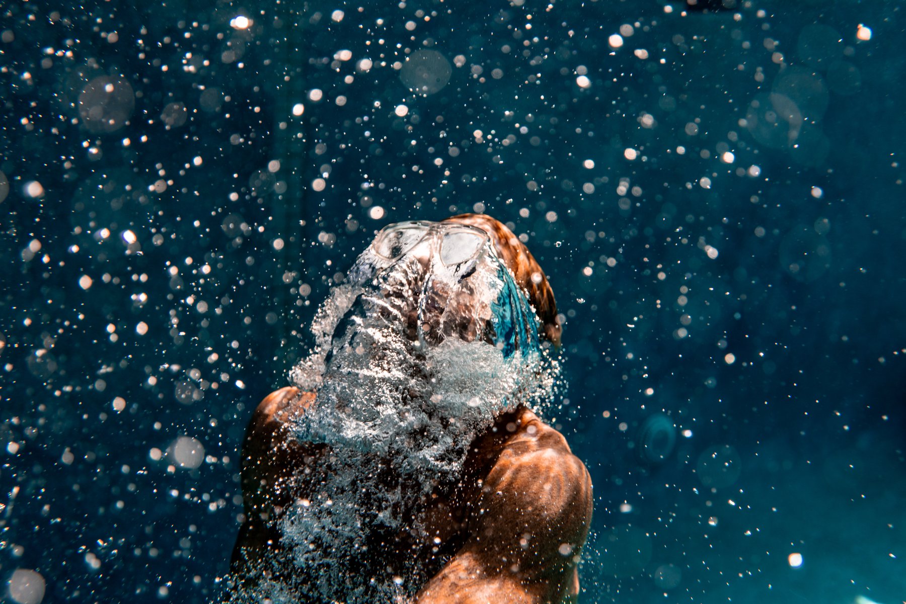 Underwater portrait of a swimmer ascending through bubbles